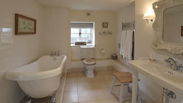 Ein Badezimmer mit freistehender Badewanne, Toilette, Waschbecken und Waschtisch.