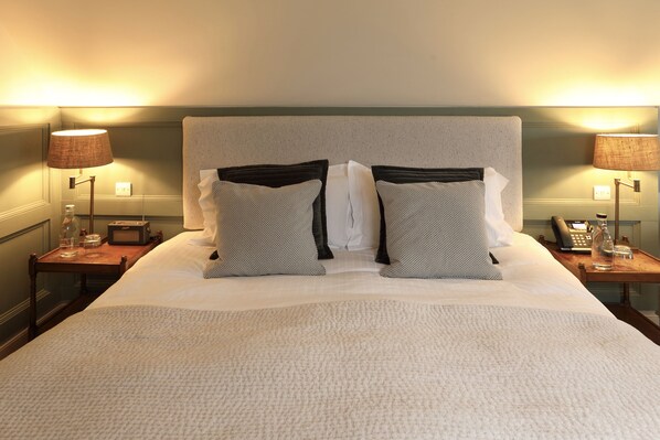 A neatly made bed with a white duvet, two pillows with black and white patterns, and two bedside lamps on wooden nightstands.