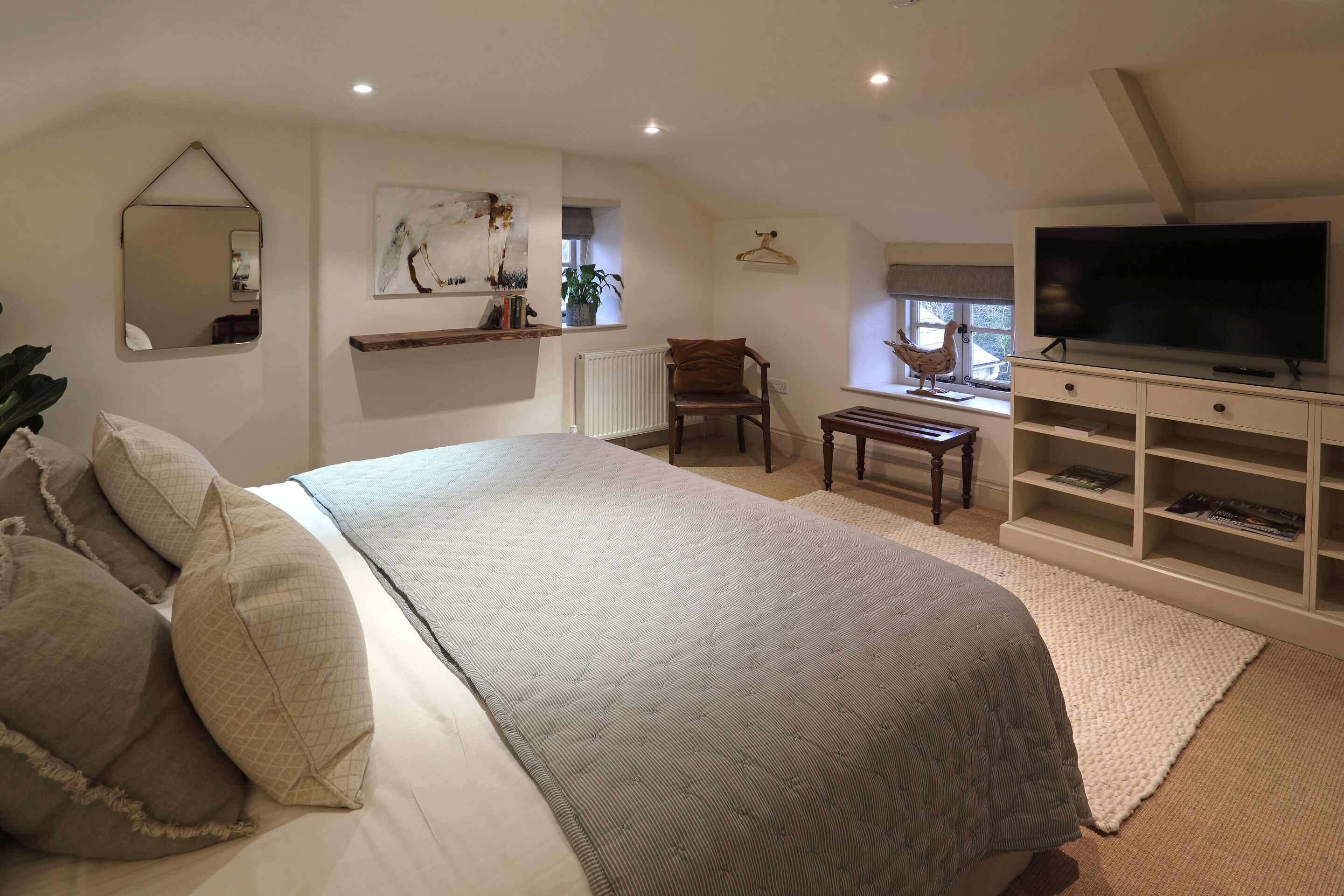 A bedroom with a large bed, a TV, a chair, and a bookshelf.