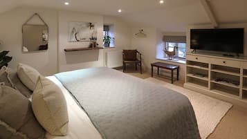 A bedroom with a large bed, a TV, a chair, and a bookshelf.