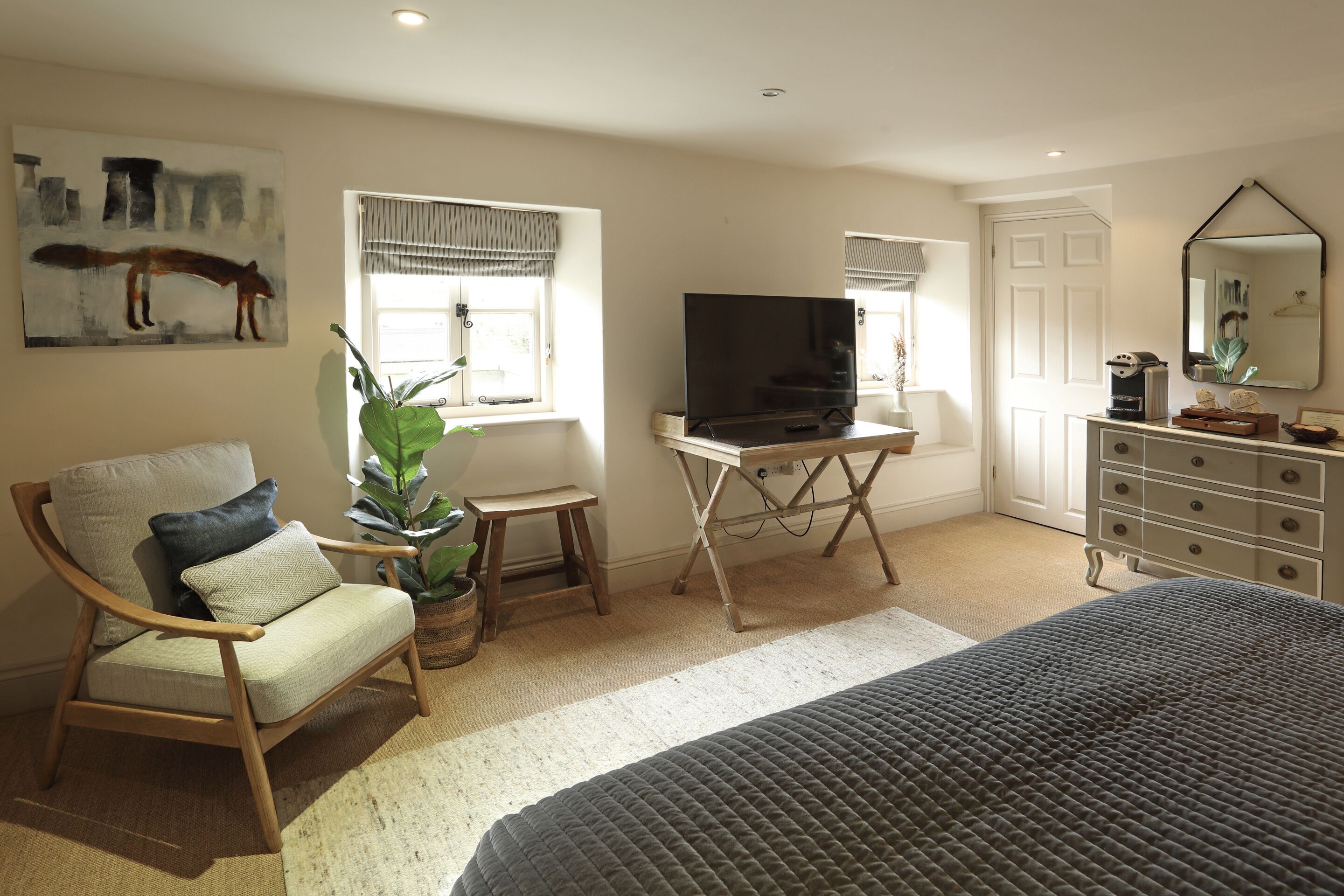 A bedroom with a bed, a chair, a TV, a dresser, and a painting on the wall.