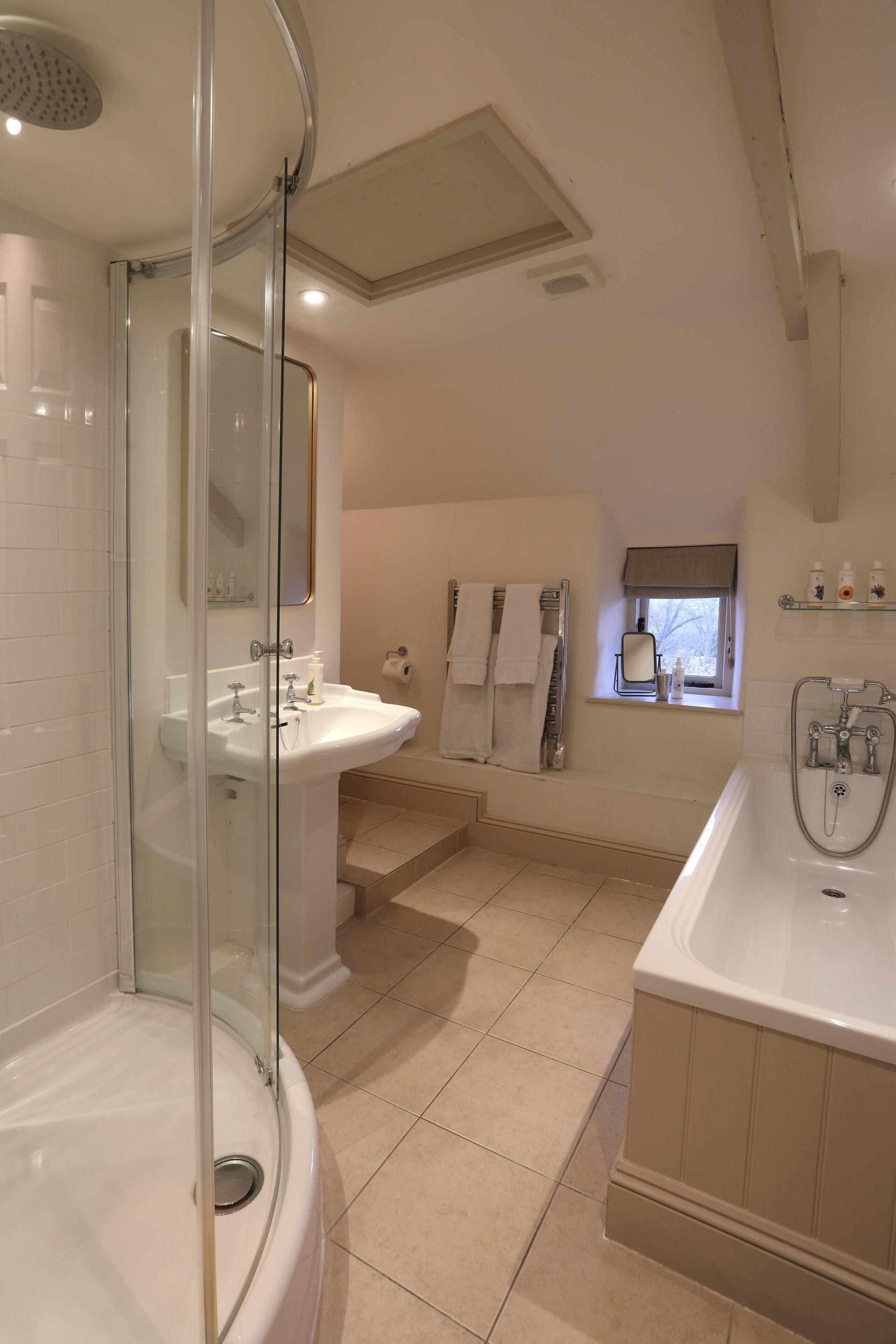 A modern bathroom with a glass-enclosed shower, a sink, a bathtub, and a window with a view.