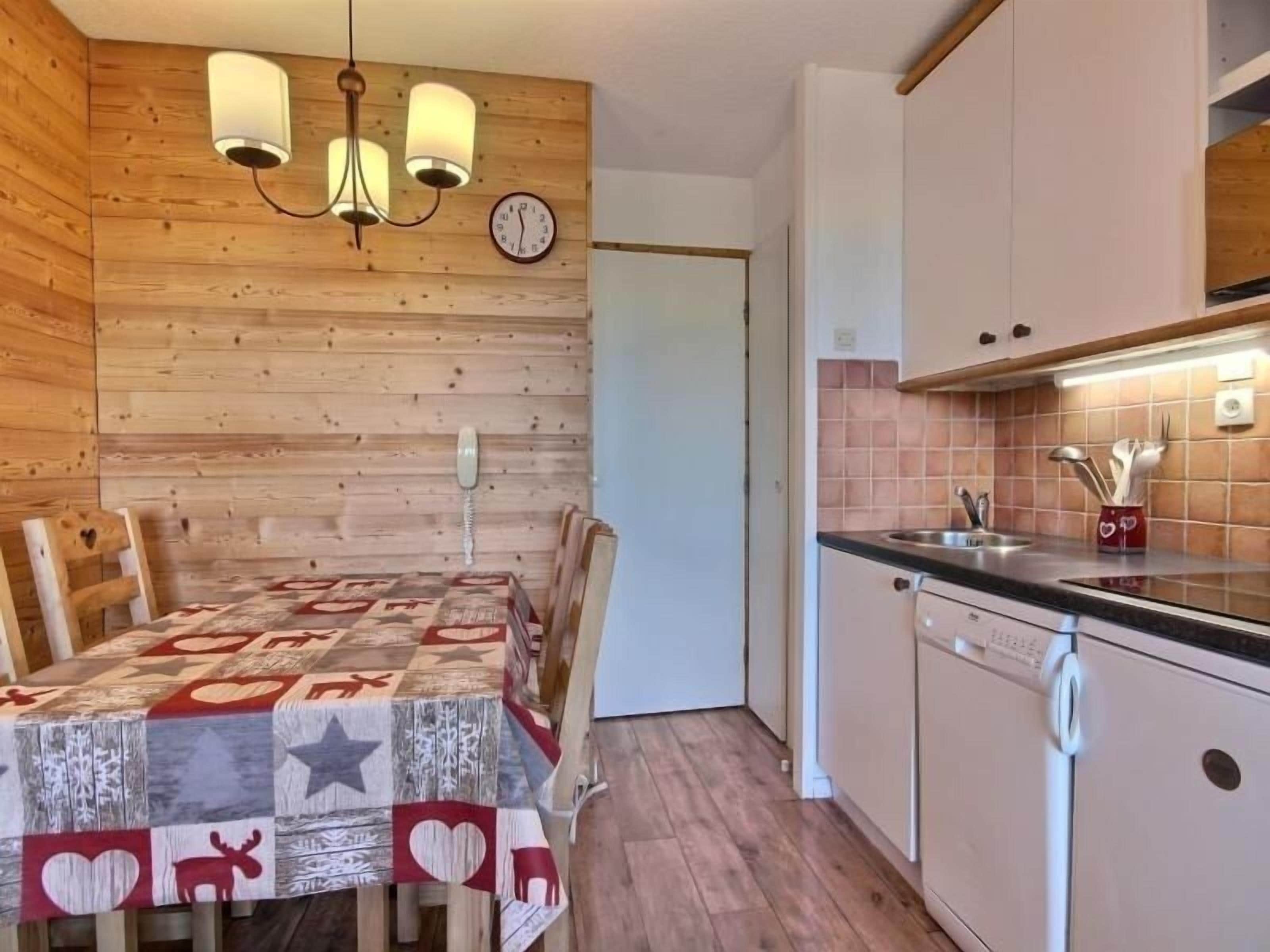 Una cocina acogedora con paredes de madera, una mesa de comedor con mantel estampado y un reloj en la pared.