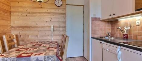 Una cocina acogedora con paredes de madera, una mesa de comedor con mantel estampado y un reloj en la pared.