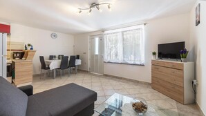 Un soggiorno moderno con un divano, un tavolino in vetro, una televisione e un'area pranzo con sedie e tavolo.