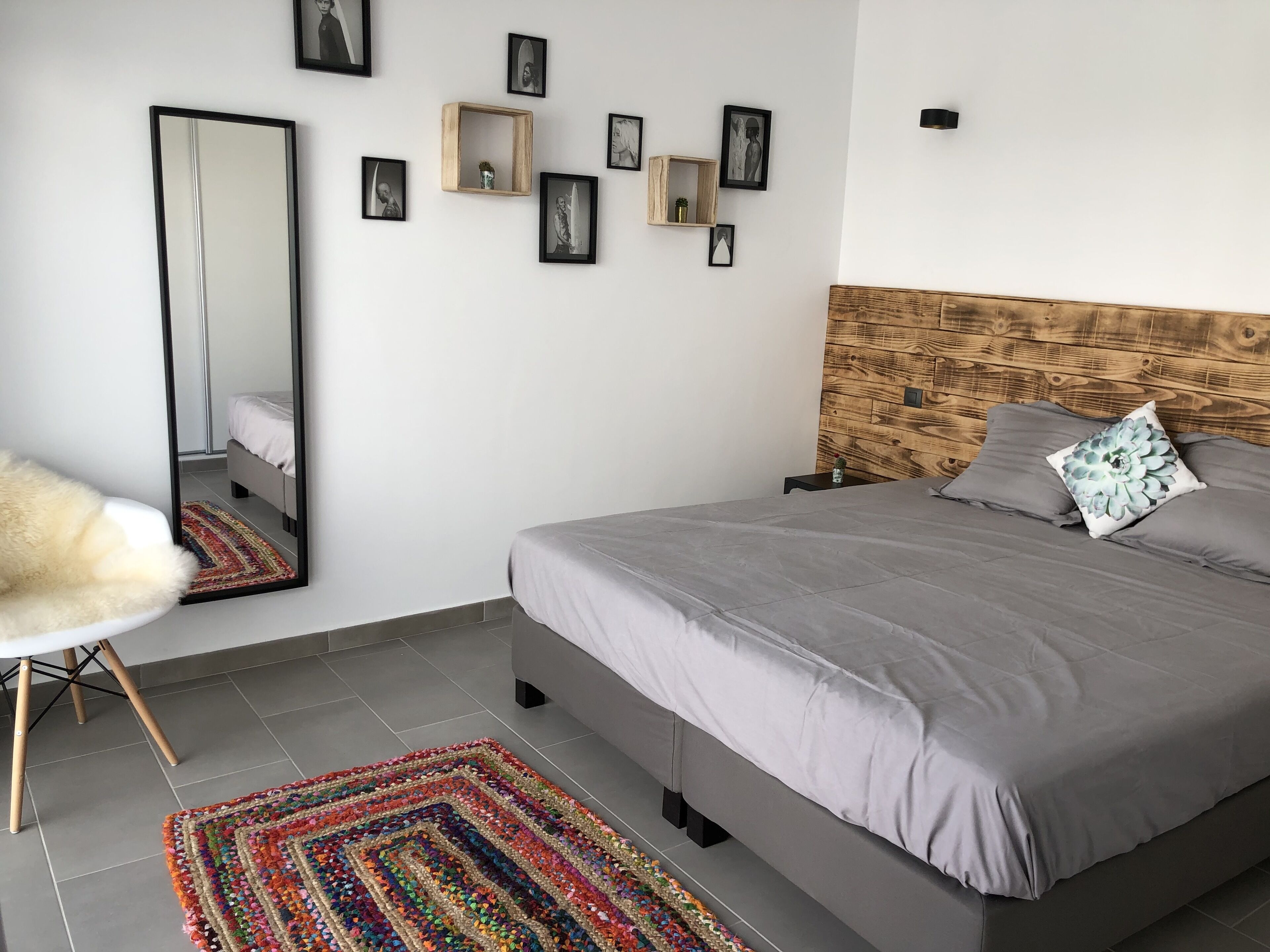 Un dormitorio con cama, espejo, alfombra y cuadros en la pared.