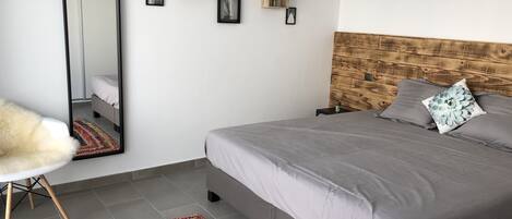Un dormitorio con cama, espejo, alfombra y cuadros en la pared.