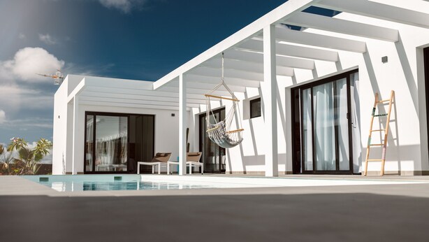 A modern house with a pool, a hanging chair, and a ladder. - Brand new and modern villa in Lajares (Fuerteventura) with heated pool (Lajares - Fuerteventura)