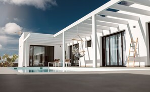 Ein modernes Haus mit Pool, Hängesessel und einer Leiter.