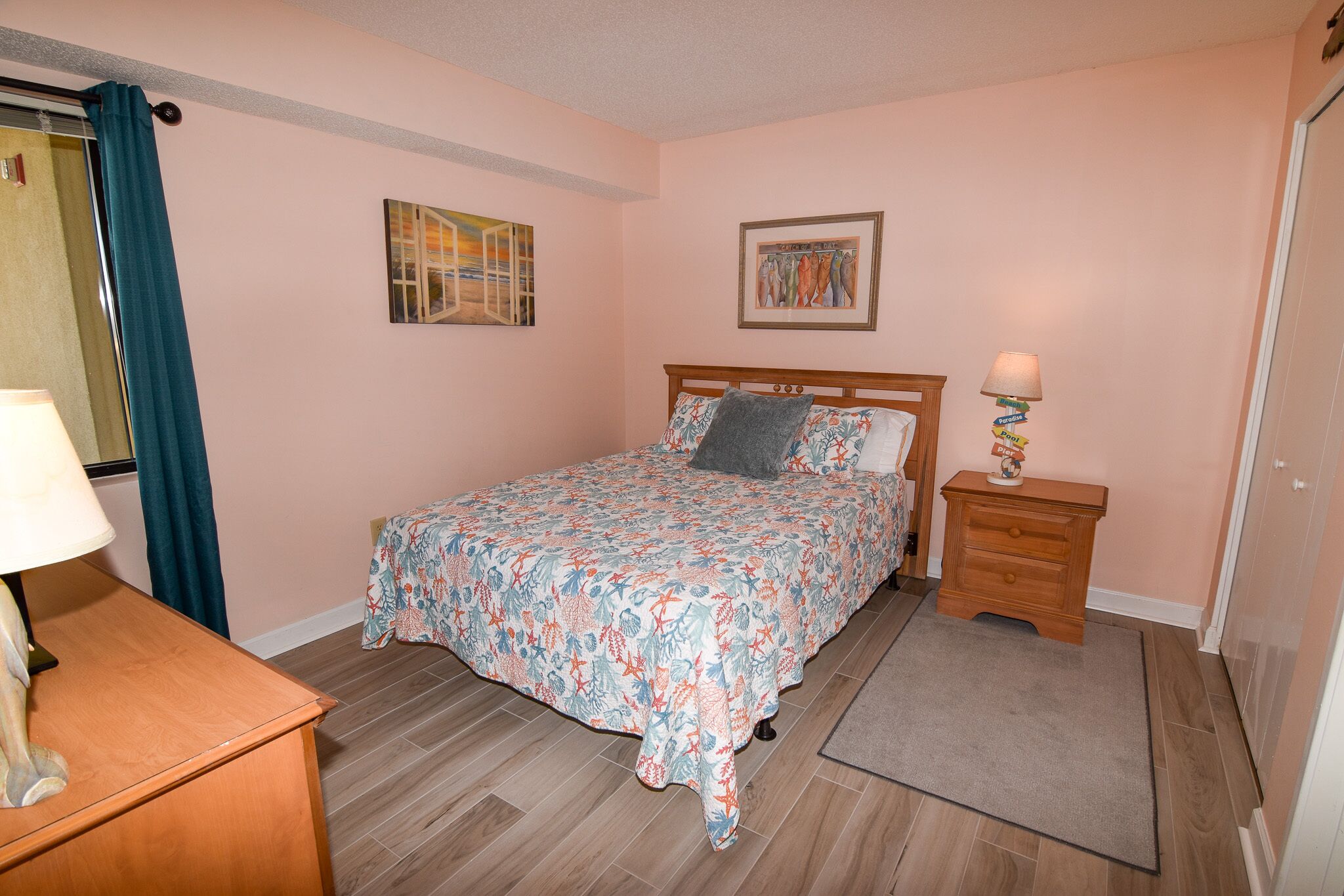 Une chambre à coucher avec un lit, une table de chevet, une lampe, une petite table et une porte.