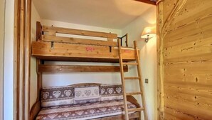 Un letto a castello con una scaletta, un cuscino decorato e un punto luce fissato al muro.