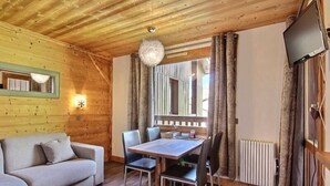 Una stanza accogliente con soffitto in legno, un tavolo da pranzo con sedie, un divano e un grande specchio.