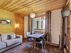 Une pièce chaleureuse avec un plafond en bois, une table à manger avec des chaises, un canapé et un grand miroir.
