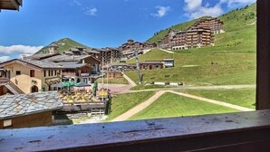 Una località montana con edifici in stile chalet, una seggiovia e una vista chiara delle colline circostanti.