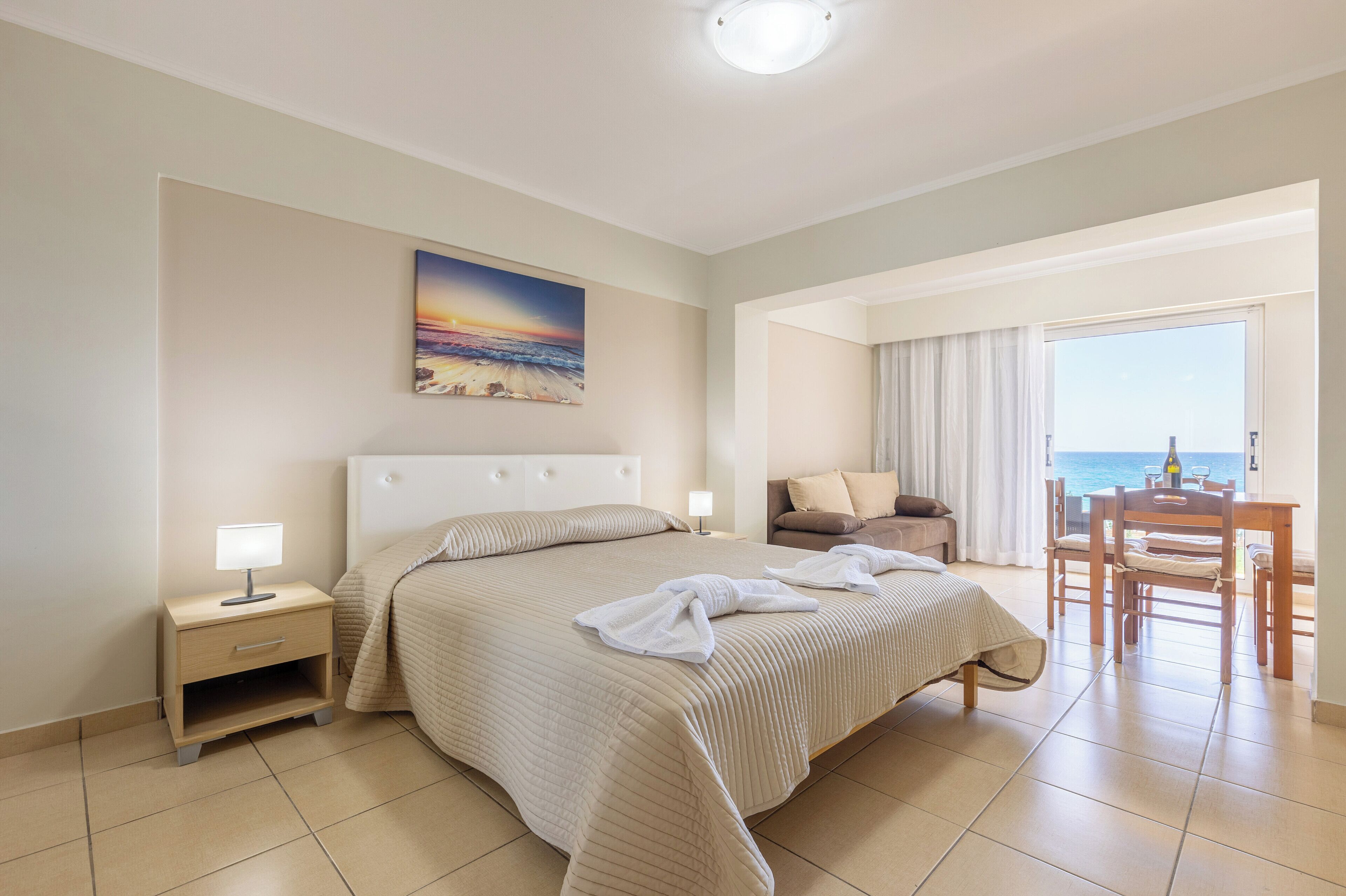 A hotel room with a bed, bedside table, and a view of the sea.