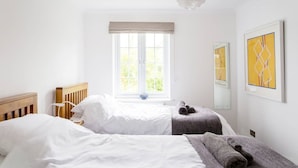 Een slaapkamer met twee bedden, een groot raam en kunst aan de muur.