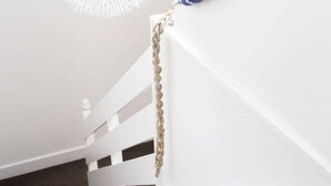 Een trap met een witte leuning en een handrail van blauw en wit touw.