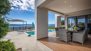 A modern outdoor patio with a pool, wicker furniture, and a view of the sea. - Stunning home in Crikvenica (Crikvenica)