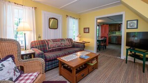 A cozy living room with a plaid sofa, a wooden coffee table, and a television on a stand. - Ironwood: Amazing Keuka Lake Views! (Hammondsport)