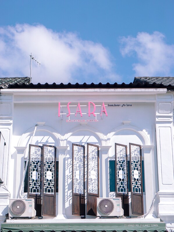 A boutique hotel with a sign reading "ISARA BOUTIQUE HOTEL & CAFE" and a location address "72 KRABI RD. PHUKET, TOWN". - Isara Boutique Hotel and Cafe (Phuket)