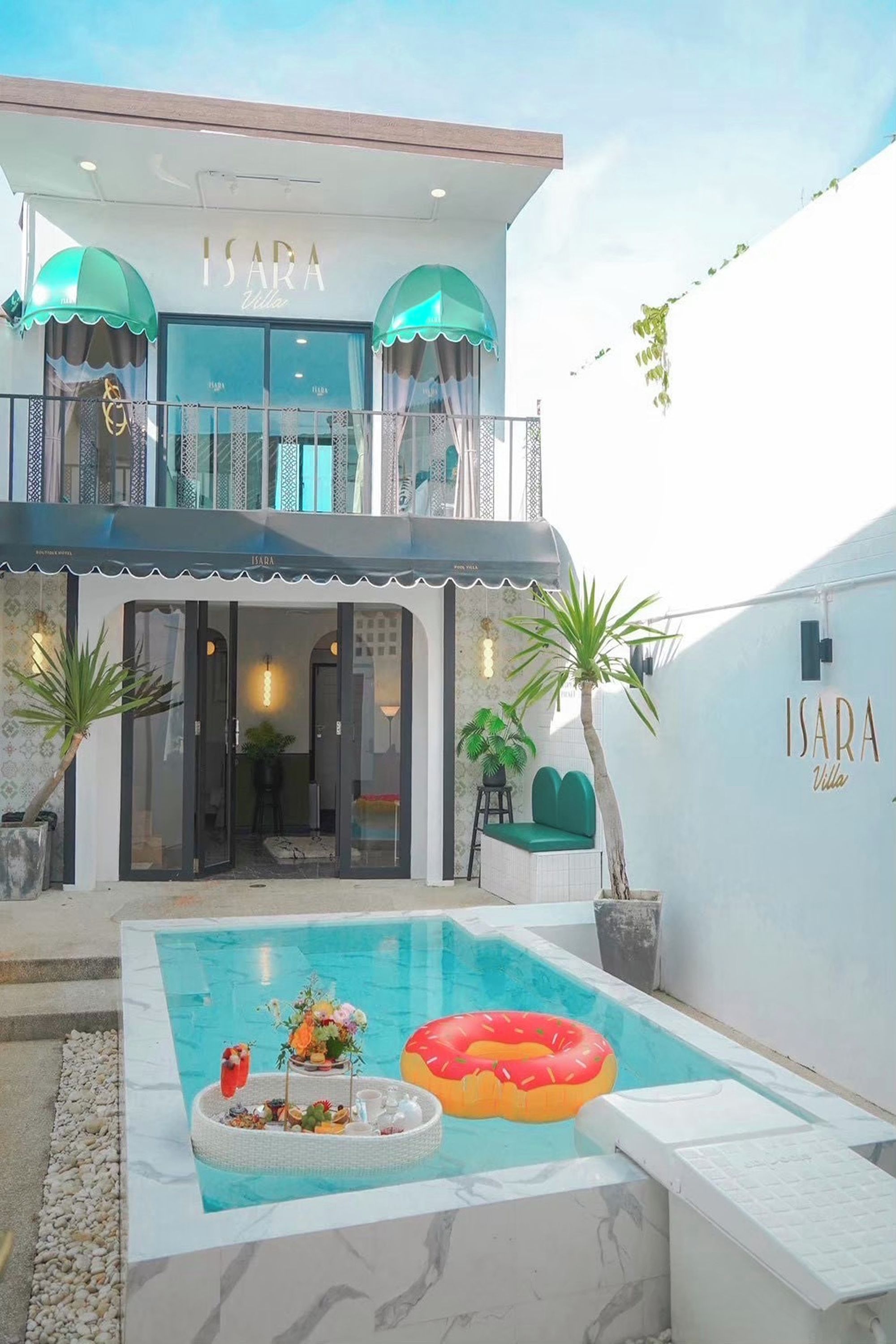 A modern hotel with a pool, outdoor seating, and a balcony with umbrellas.