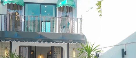 A modern hotel with a pool, outdoor seating, and a balcony with umbrellas.