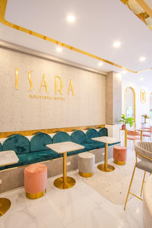 A modern hotel lobby with a seating area featuring teal sofas and gold accents. - Isara Boutique Hotel and Cafe (Phuket)