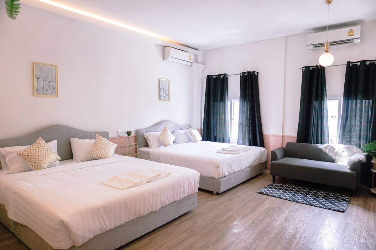 Habitació d'hotel amb dos llits, un sofà i una taula petita.