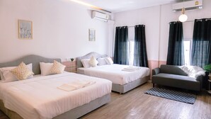 A hotel room with two beds, a sofa, and a small table.