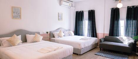A hotel room with two beds, a sofa, and a small table.