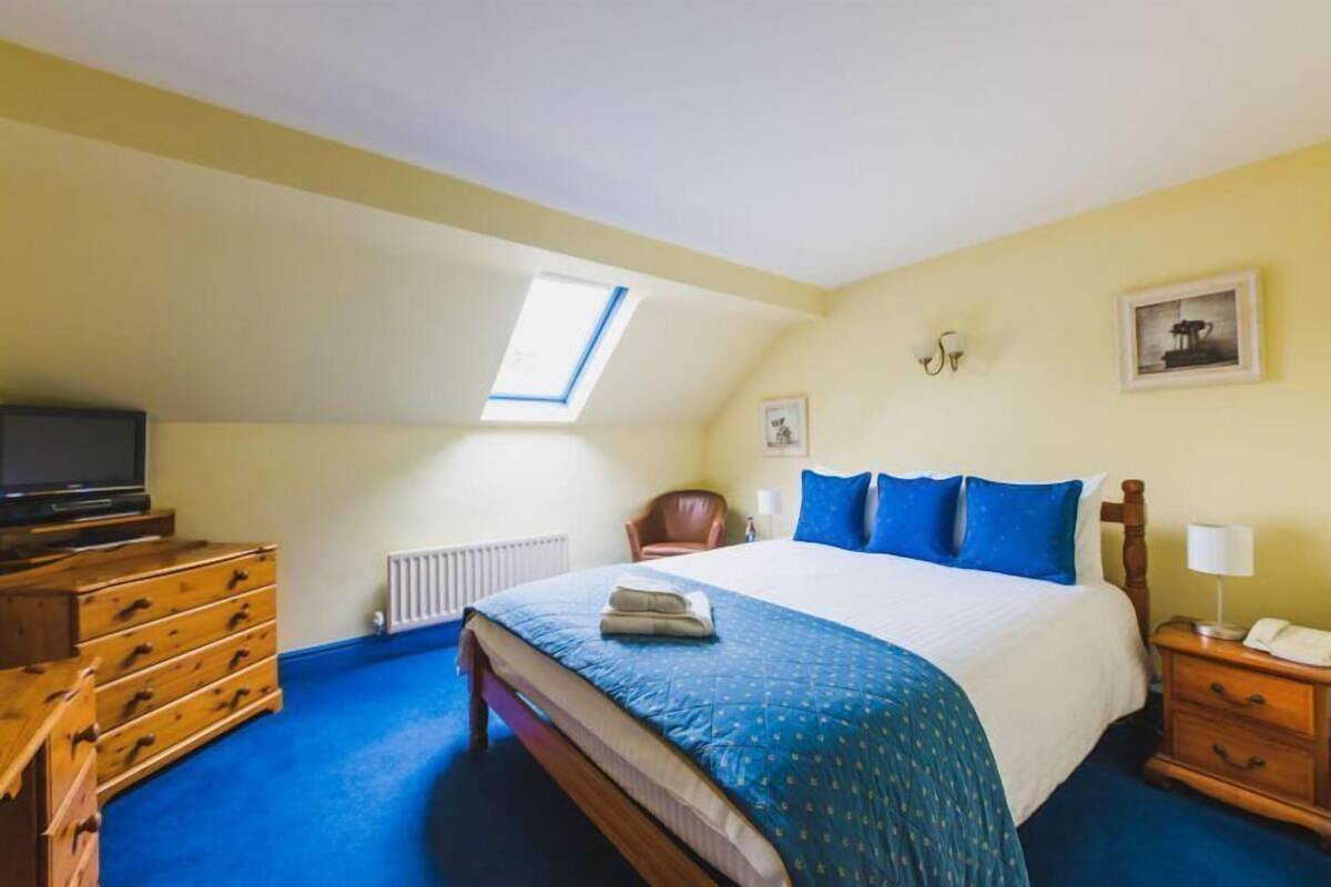 A bedroom with a bed, a dresser, a chair, a nightstand, a lamp, and a ceiling light.