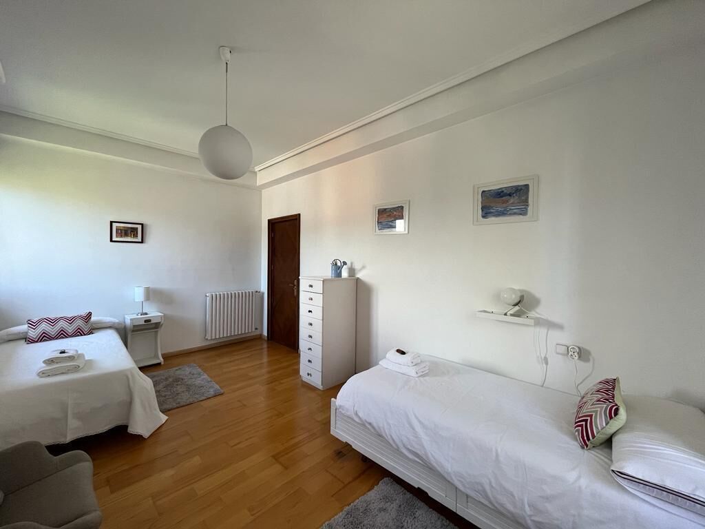 Et moderne hotelværelse med to senge, en kommode, et skrivebord og en radiator.