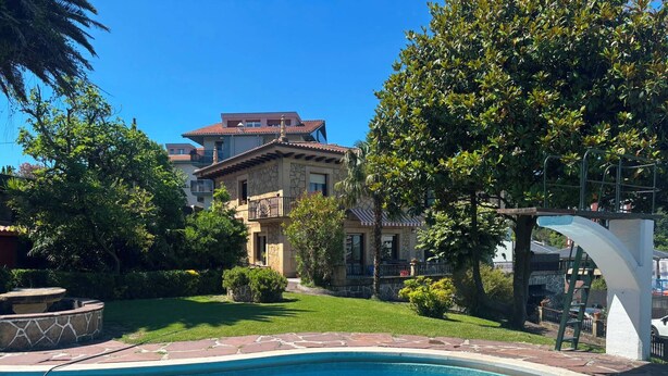 A swimming pool with a stone border, a well-maintained lawn, and a two-story building with a balcony in the background. - Sasueta Manor House 5 minutes from downtown (Donostia)