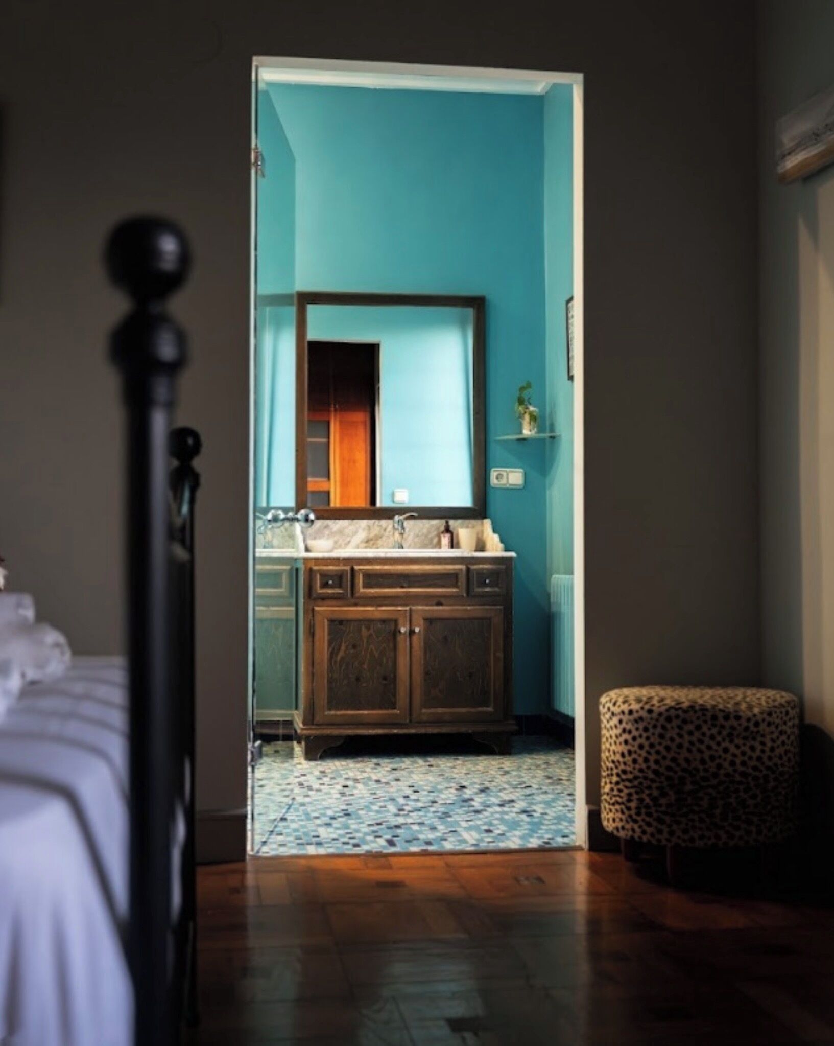 Una camera da letto con un letto, una cassettiera in legno, uno specchio e un pouf a stampa leopardo.