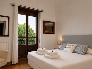 Una habitación de hotel con cama, ventana con cortinas, un cuadro en la pared y un radiador.