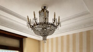 Un lit double avec une tête de lit en bois, un lustre, une fenêtre avec des stores et un mur à rayures.