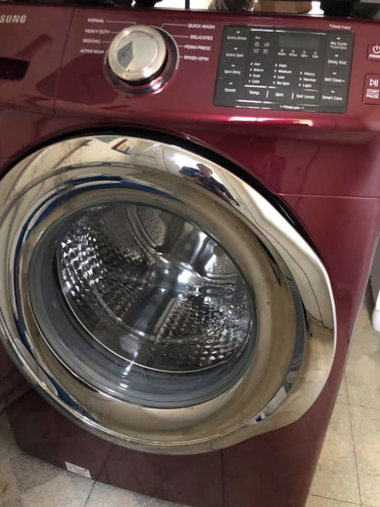 A red washing machine with a control panel displaying various settings.