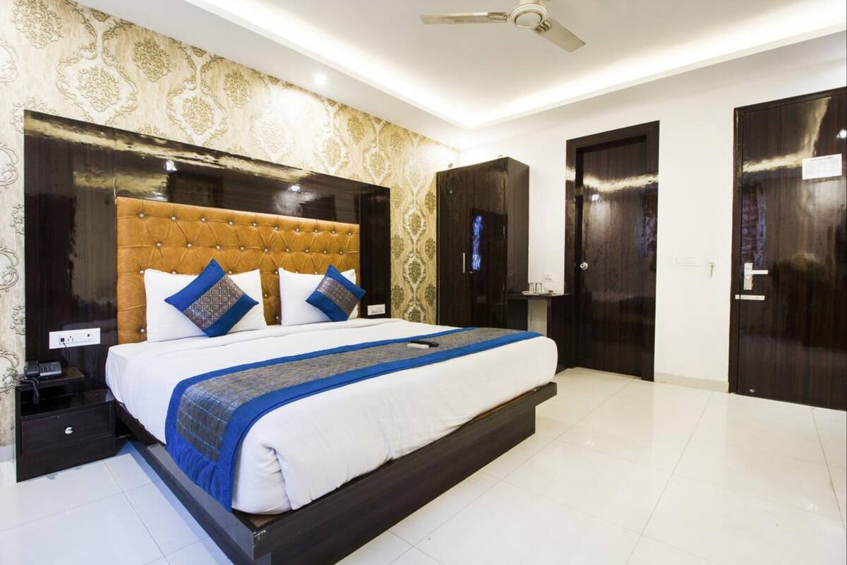 A hotel room with a large bed, dark wood wardrobe, and a ceiling fan.