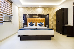 Um quarto moderno com uma cama grande, um cabeceira escura e um papel de parede estampado.