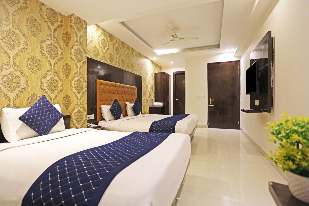 A hotel room with two beds, a large headboard, a flat-screen TV, and a ceiling fan.