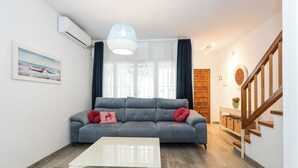 A living room with a grey sofa, a white coffee table, and a staircase.
