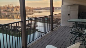 A wooden deck with a view of a lake and houses in the background. - LAKEFRONT End Unit Condo at 3 Seasons @ 21MM  (Osage Beach)