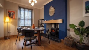 A cozy dining area with a wooden table, chairs, a fireplace, and a large mirror on the wall. - Central Home with Parking & Sky TV by LetMeStay (Cumbria)