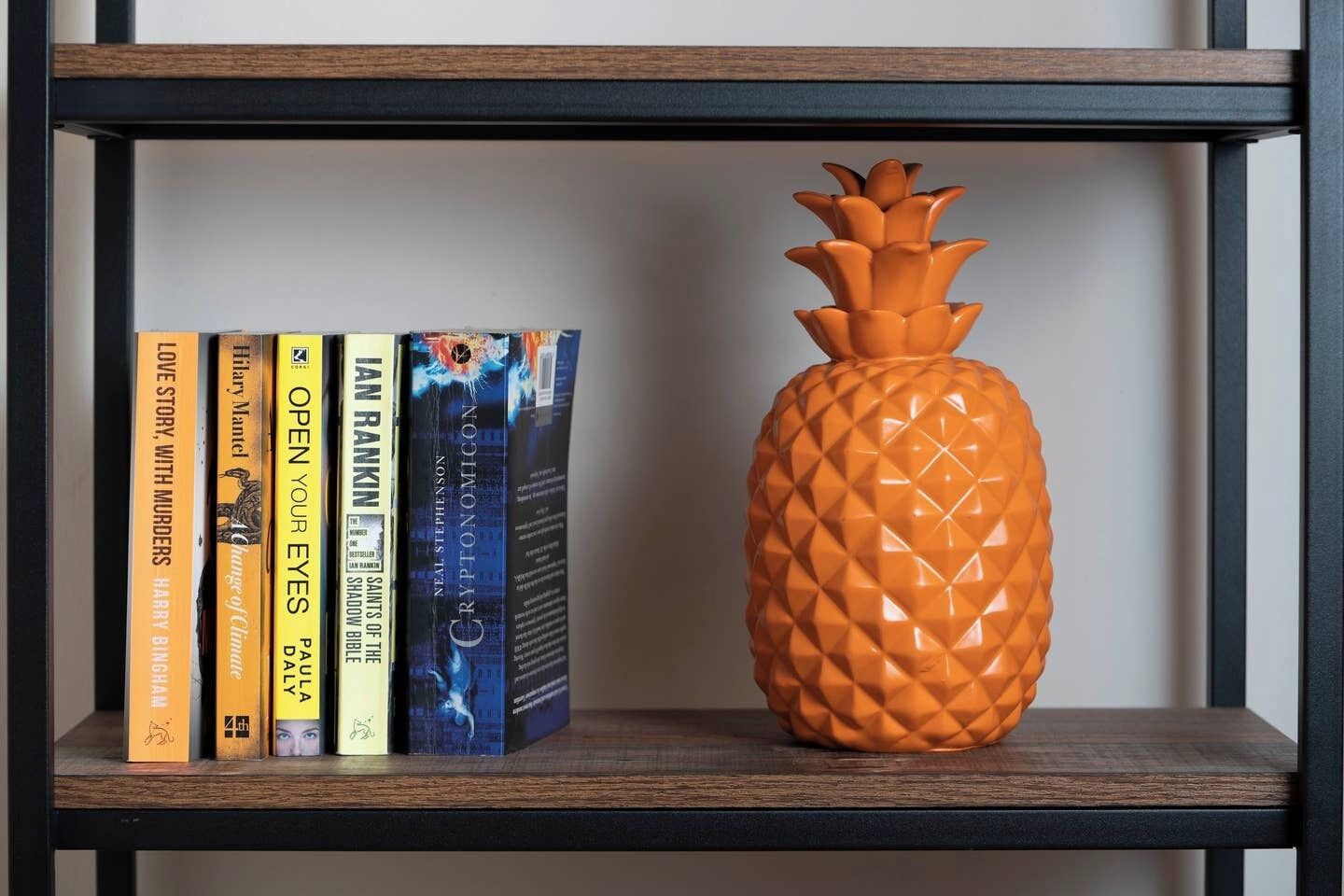 A bookshelf with books and a pineapple-shaped vase.