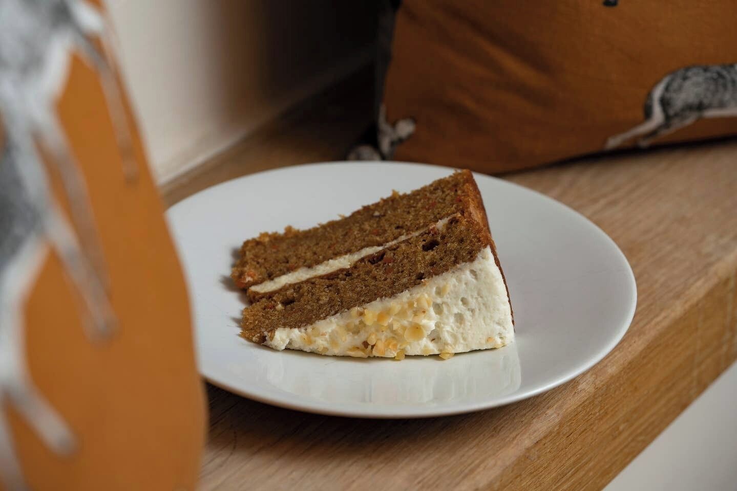 A slice of cake on a white plate on a wooden table.
