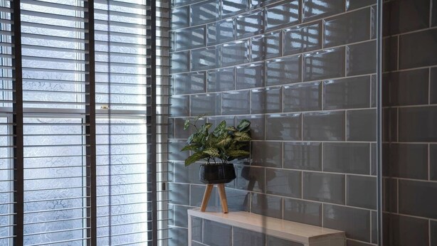 A modern interior with a tiled wall, a window with blinds, and a plant on a shelf. - Central Home with Parking & Sky TV by LetMeStay (Cumbria)