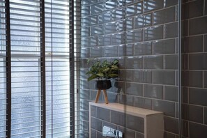A modern interior with a tiled wall, a window with blinds, and a plant on a shelf. - Central Home with Parking & Sky TV by LetMeStay (Cumbria)