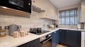 A modern kitchen with white subway tiles, a Bosch microwave, a built-in oven, and a window with blinds. - Central Home with Parking & Sky TV by LetMeStay (Cumbria)