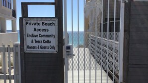 Una entrada cerrada a una zona privada de playa, con un letrero que indica que el acceso es solo para propietarios e invitados.