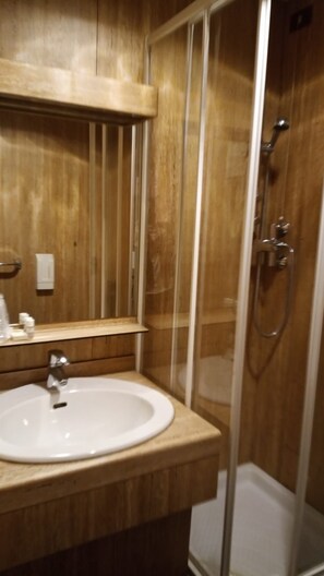 A bathroom with a wooden vanity, a sink, and a glass-enclosed shower. - Hotel Socrate (Lavena Ponte Tresa)
